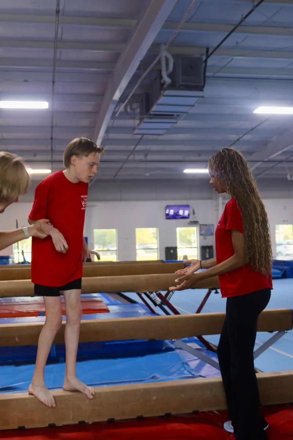 A gymnast practicing with individualized support
