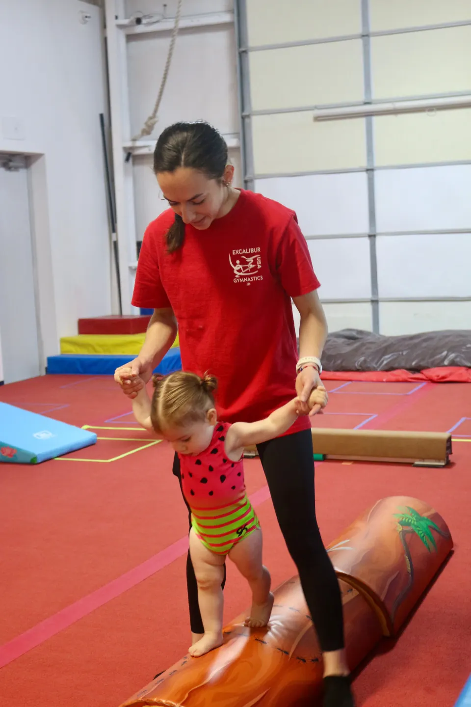 A caregiver helping a toddler explore gymnastics equipment